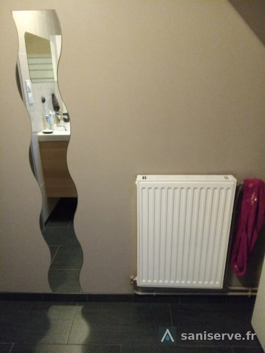 Ancien radiateur à eau chaude dans la salle de bain avant son remplacement par un sèche-serviettes