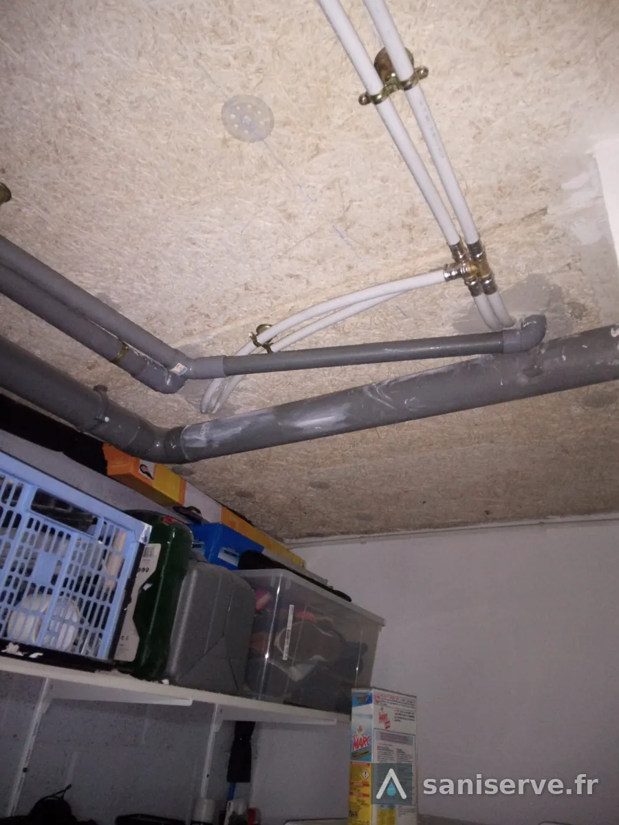 Évacuations PVC et alimentations en eau reprises au plafond du garage sous la salle de bain